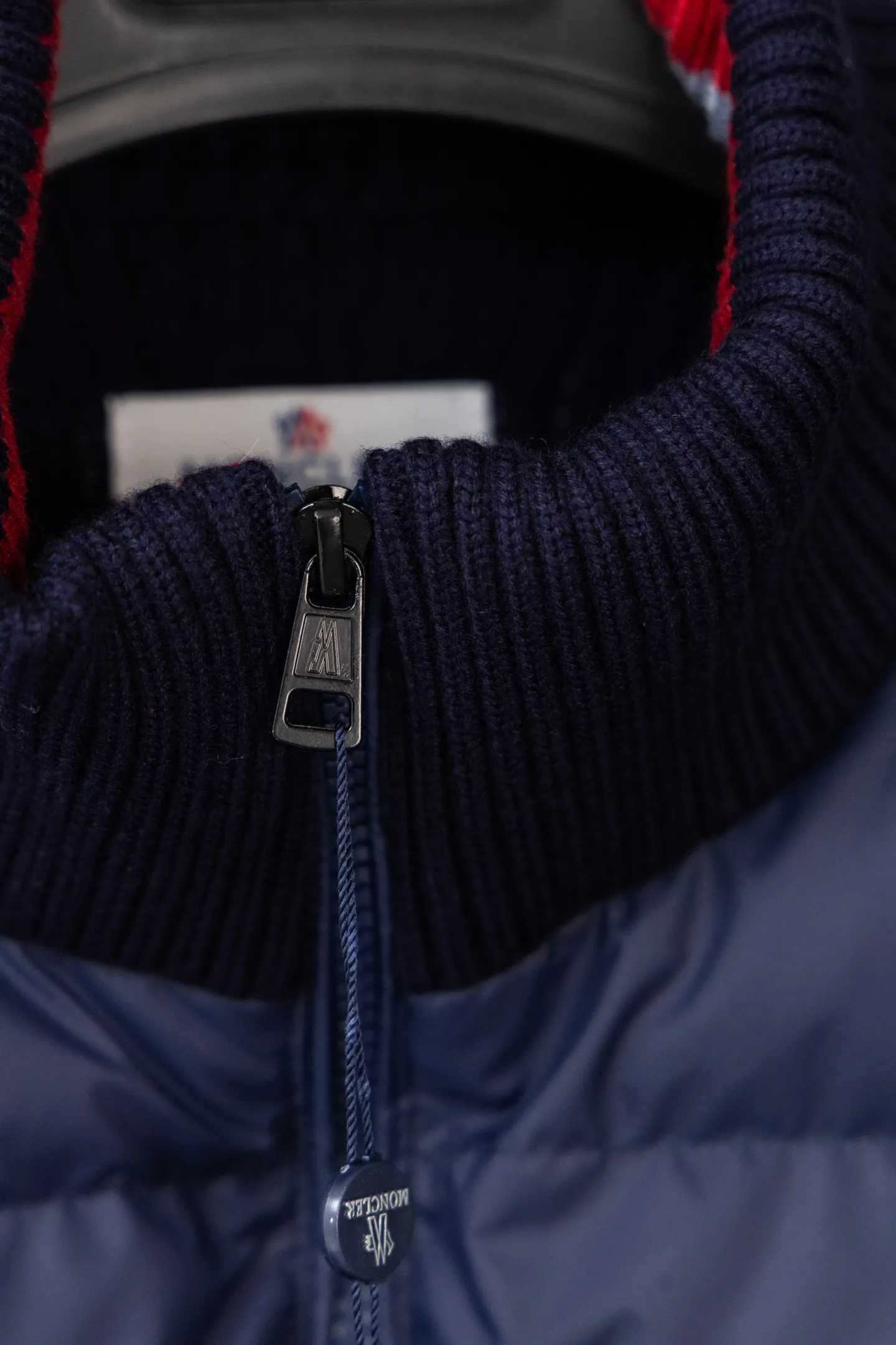 P560 Style number: M046 This is a knitted patchwork down jacket from Moncler. It combines the brand's high-end outdoor genes and fashion design. It is a luxurious item with both warmth and style in autumn and winter. Design highlights: Material splicing: Pure wool knitted sleeves are spliced ​​with a down front filled with 90 white duck down. The knitted part is soft and breathable, and the down part is fluffy and warm, achieving a dual fusion of style and function.  Detailed logo: The iconic Moncler badge pocket on the left arm is a classic embodiment of brand recognition; the stand-up collar design with a two-way zipper not only improves warmth, but also strengthens the neat styling.  Color embellishment: The contrasting red and blue stripes on the cuffs and hem inject vitality into the overall black tone, adding a retro college style charm. Craftsmanship and Quality: The down filling follows the European standard 90 down standard, with excellent fluffiness and down filling, with almost no stiff feeling. At the same time, it adopts the "line first and then separate down filling" process. The four-layer liner effectively prevents down from being drilled, and can maintain warmth even after long-term wear.  The knitted part is made of high-quality wool, which has a delicate touch and is not easily deformed. The splicing process with the down fabric is rigorous, showing a high-end texture level.  Style and Wearing This down jacket is based on the classic college style. The slim straight version can modify the body line and can be easily adapted to a variety of styles: it can be paired with jeans and casual shoes for a casual look on a daily basis. It can also be upgraded to an urban light luxury style by layering it with a turtleneck sweater inside and a suit outside. It is a key item in the winter wardrobe that is both practical and fashionable. Color: black, navy blue, sizes S-XL